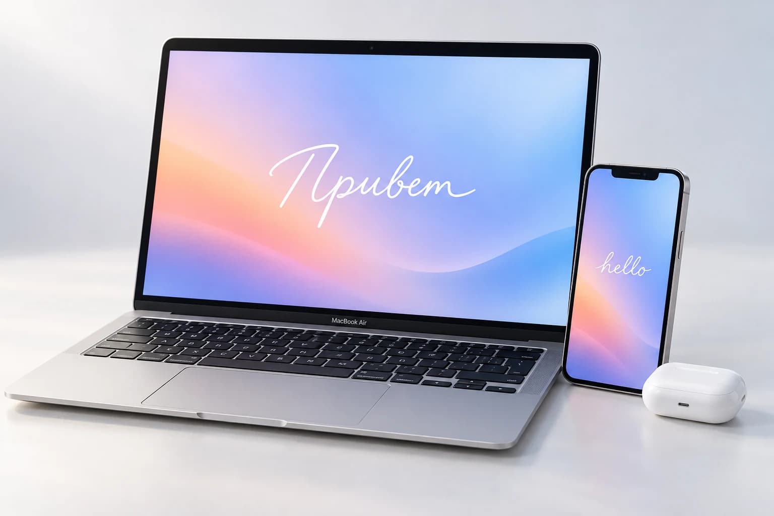 MacBook с надписью «Привет», iPhone и AirPods в мягком свете