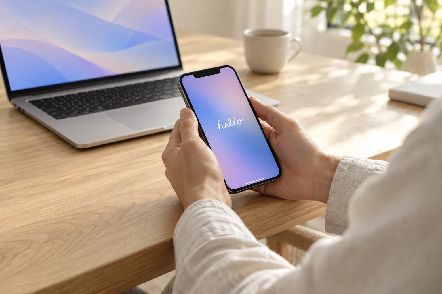 Первое включение iPhone за светлым рабочим столом рядом с MacBook